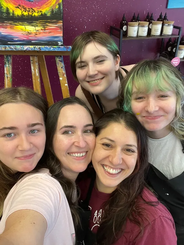 Five teens and adults smiling together during a creative workshop